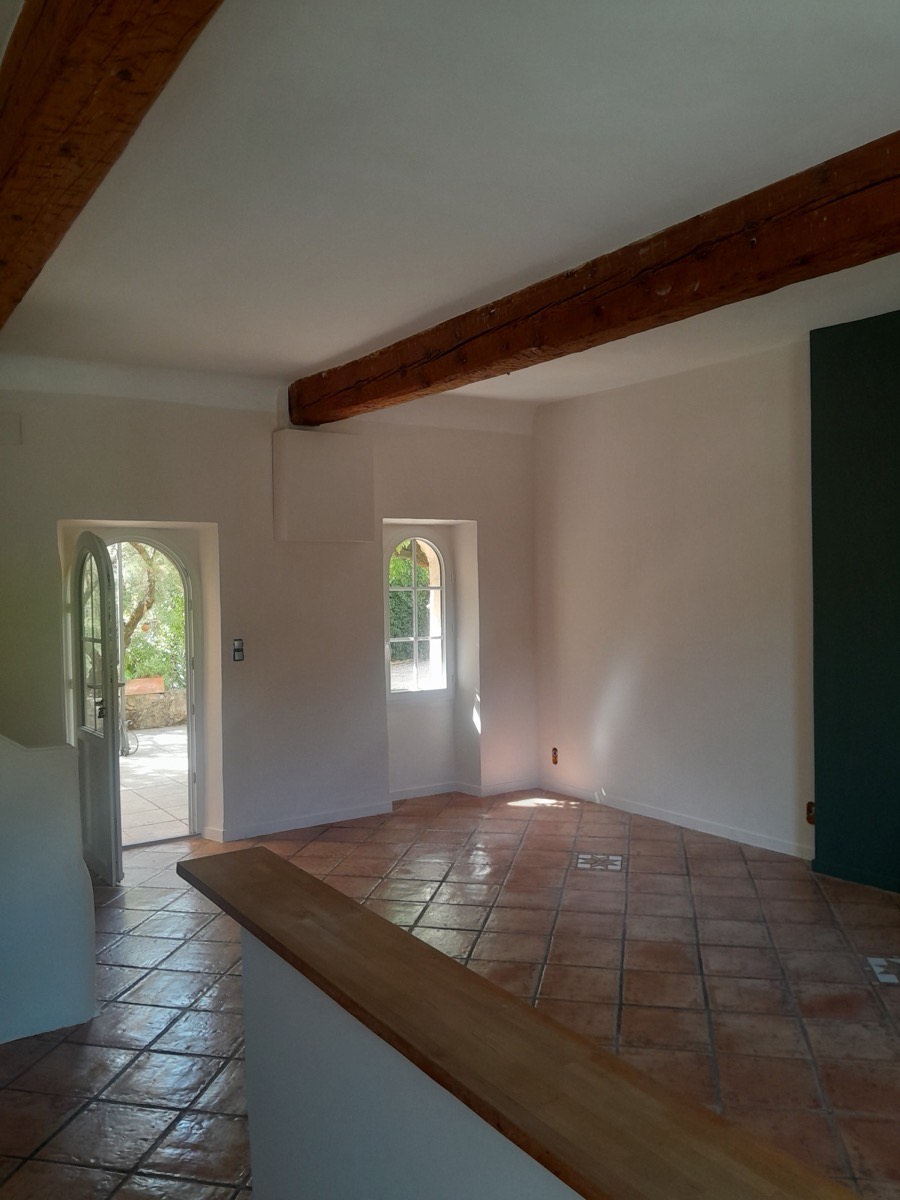 Pièce à vivre avec poutre bois, portes cintrées et sol en tomettes