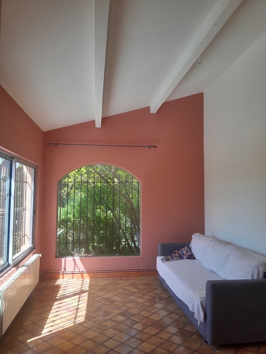 Pièce avec mur terracotta, poutres blanches et fenêtre cintrée