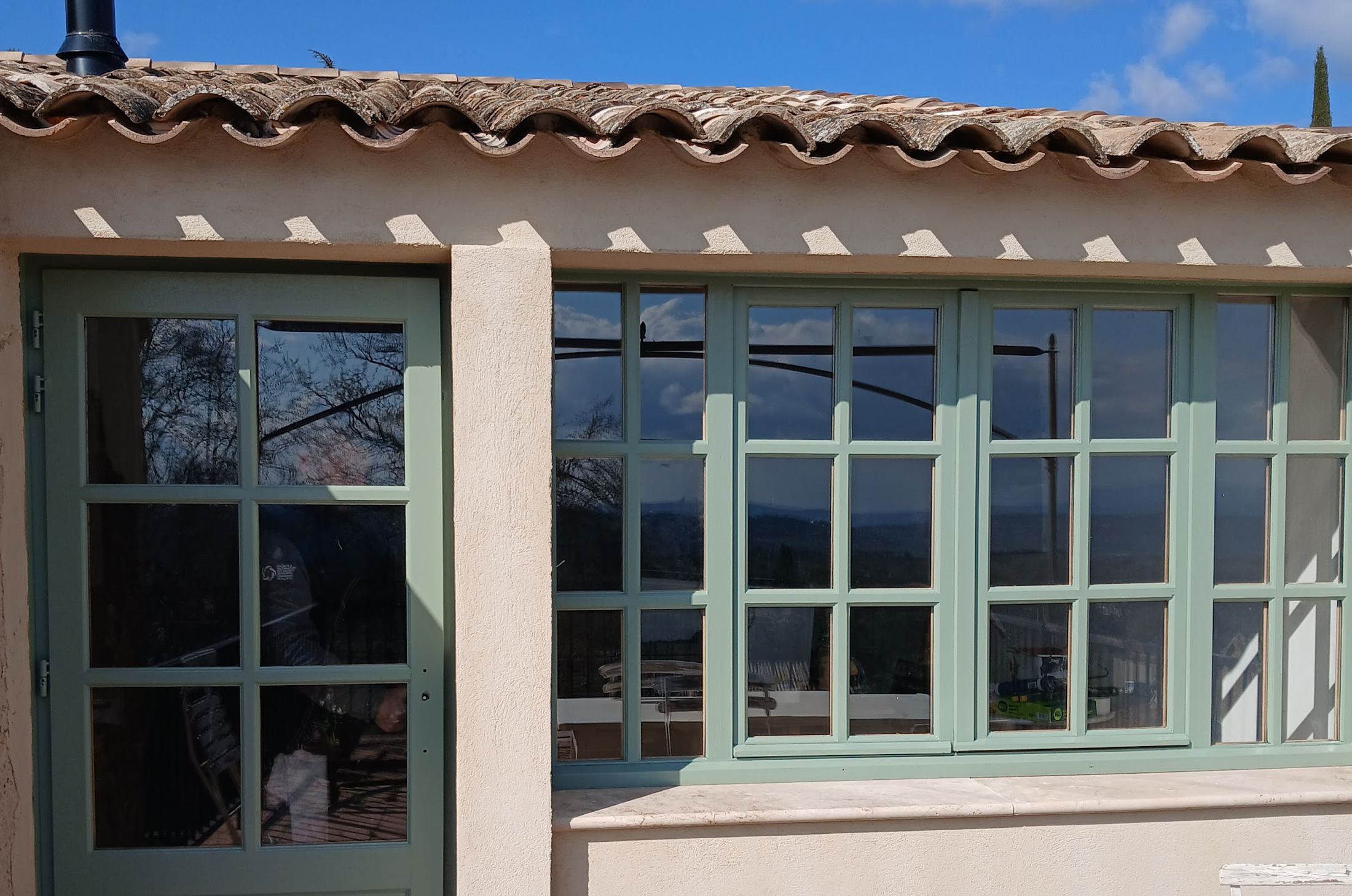 Menuiseries et boiseries repeintes en vert-de-gris par FC Peinture sur une véranda provençale du Luberon