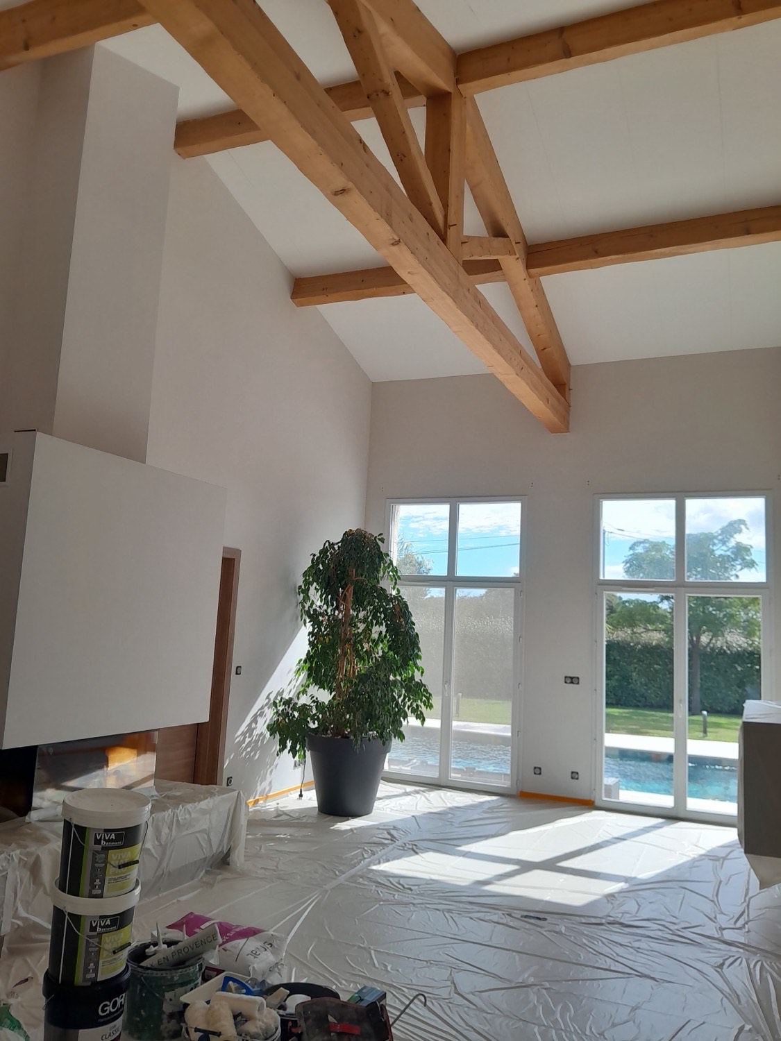 Séjour cathédrale d'une villa avec poutres bois et vue piscine